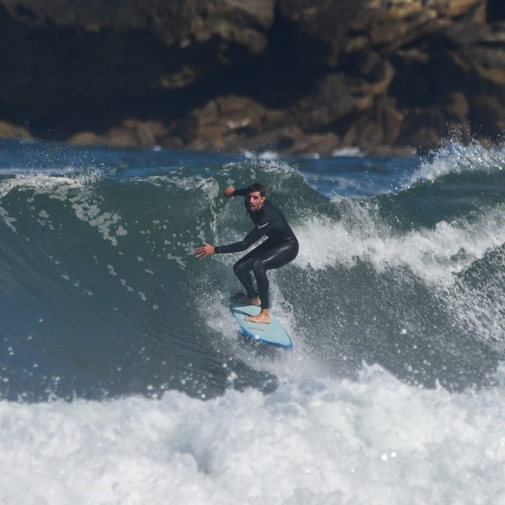Un surfista baja por la pared de una ola en la Zurriola.