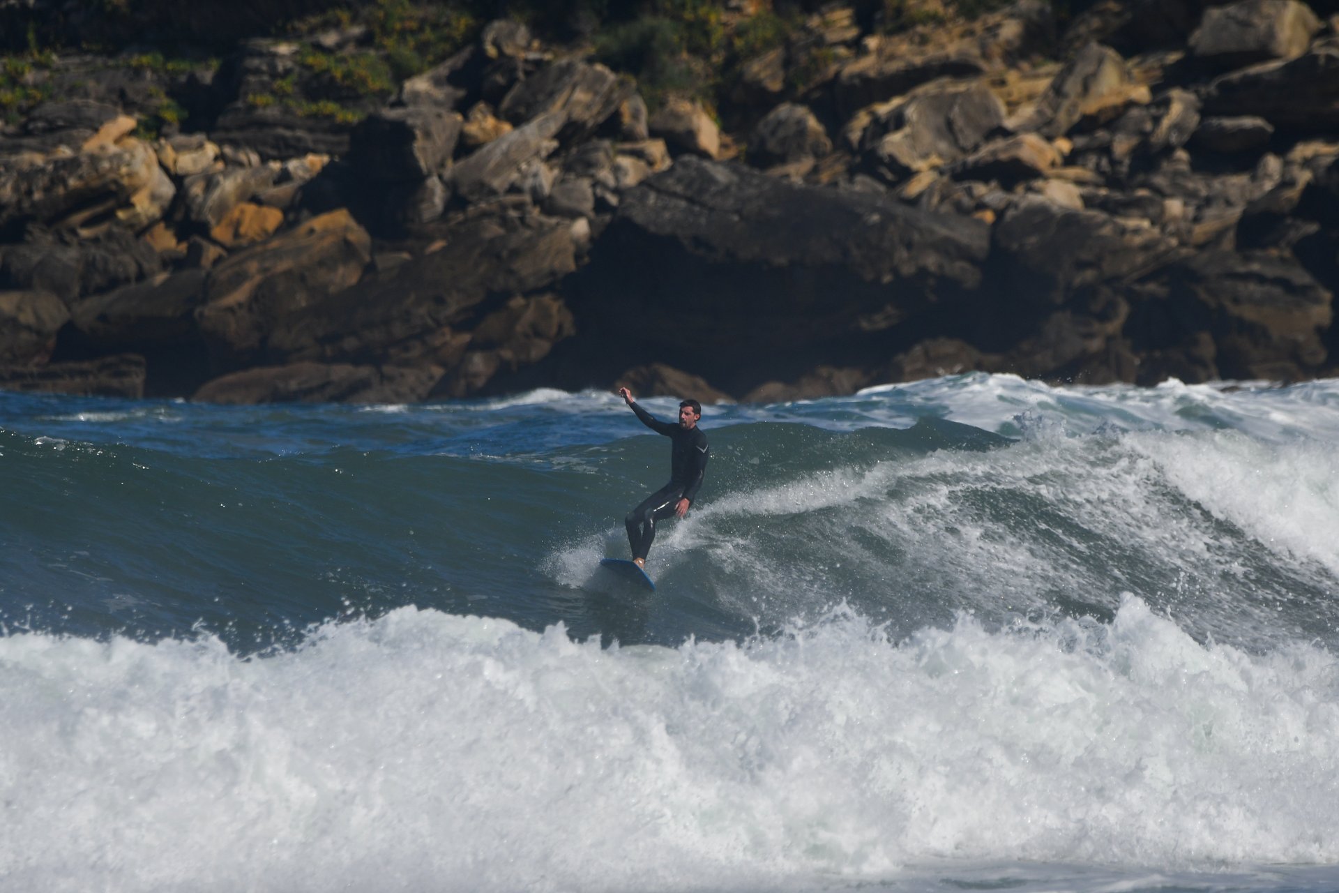 Un surfista de pie sobre la tabla en una ola de la Zurriola.